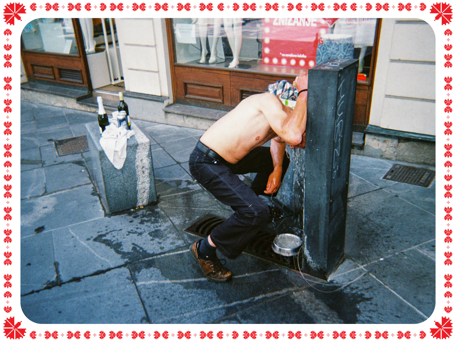 Moški brez majice se nastavlja curku vode na javnem pitniku.